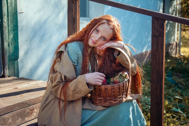 Portret van een mooi roodharig meisje met lang haar met appels in de herfst