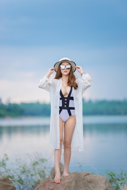 Portret van een mooie aziatische sexy vrouw die 's avonds een bikini aan de rotskant van de zee draagtLevensstijl van moderne vrouwenThailand-mensen