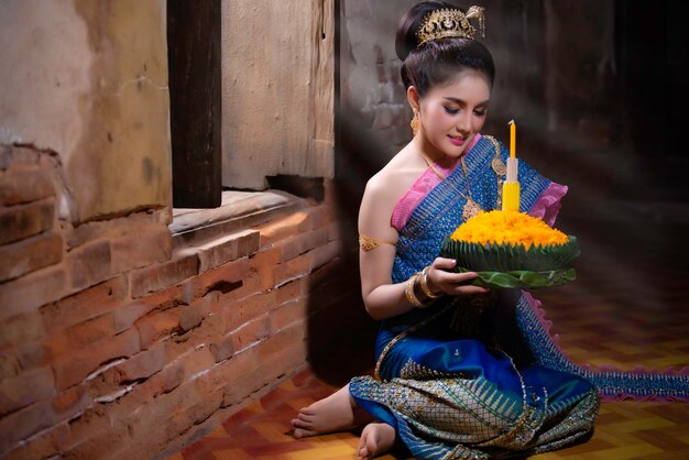 Portret van een mooie aziatische vrouw in een traditionele Thaise klederdracht die kratong vasthoudt voor deelname aan het loy kratong-festival in thailand