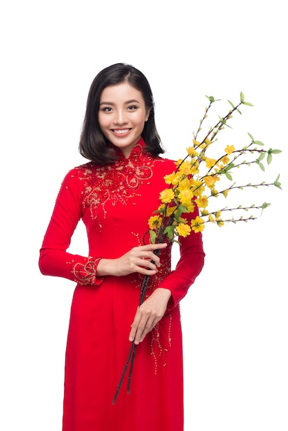 Portret van een mooie Aziatische vrouw op traditioneel festivalkostuum Ao Dai met Hoa Mai-boom (Ochna Integerrima) bloem. Tet vakantie. Nieuw maanjaar.