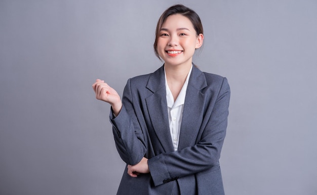 Portret van een mooie Aziatische zakenvrouw op een grijze achtergrond