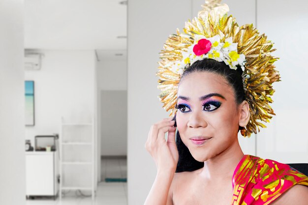 Portret van een mooie Balinese danseres die make-up foundation op haar gezicht aanbrengt