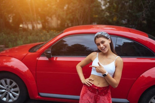 Portret van een mooie blanke vrouw die tegen een nieuwe rode auto staat