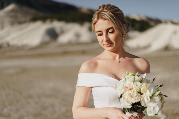 Foto portret van een mooie blonde bruid in een witte jurk met blote schouders