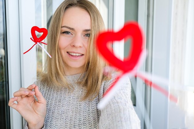 Foto portret van een mooie blonde gelukkige vrouw met een symbool hart twee rode harten meisje die een selfie maakt