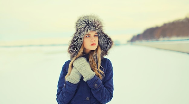 Portret van een mooie blonde jonge vrouw die buiten in een winterhoed poseert