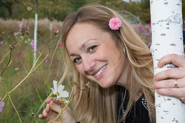 Portret van een mooie blonde vrouw met een bloem in het haar