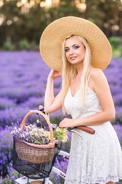 Portret van een mooie blonde vrouw met een fiets in lavendel.