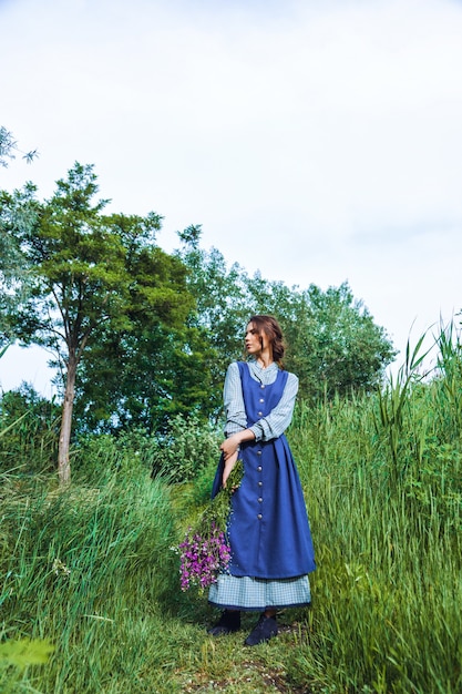 Portret van een mooie brunette vrouw in blauwe jurk in het veld