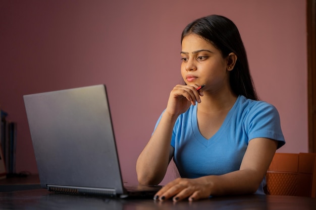 Portret van een mooie en jonge Indiase vrouw die op haar laptop werkt