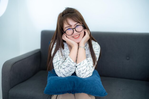 Foto portret van een mooie gelukkige glimlachende aziatische vrouw die ontspant op een comfortabele bank.