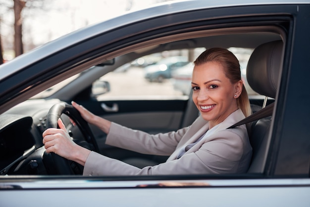 Portret van een mooie gelukkige vrouw besturen van een auto, glimlachend in de camera.