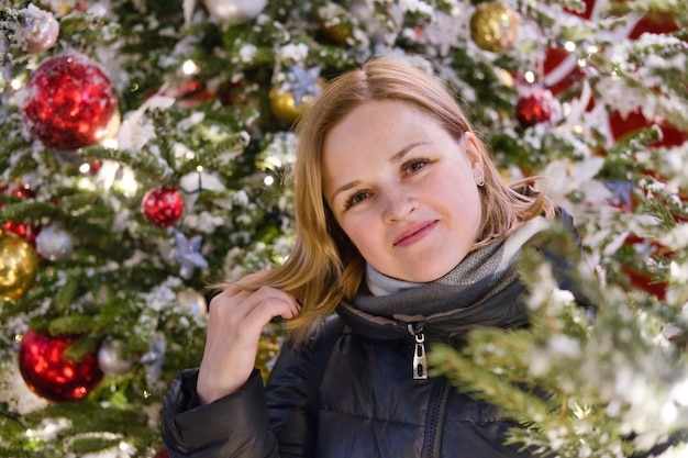 Portret van een mooie glimlachende Europese vrouw op achtergrond van een kerstboom