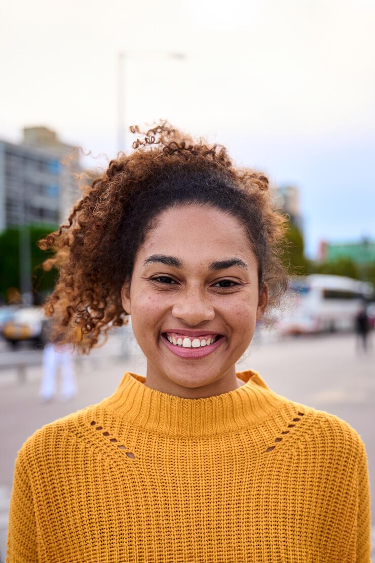 Foto portret van een mooie glimlachende jonge afrikaanse vrouw met krullend haar die naar de camera kijkt met een positieve uitdrukking