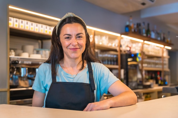 Portret van een mooie glimlachende serveerster met de koffiemachine op de achtergrond de covid-beperkingen worden verwijderd en het verplichte gebruik van maskers wordt verwijderd