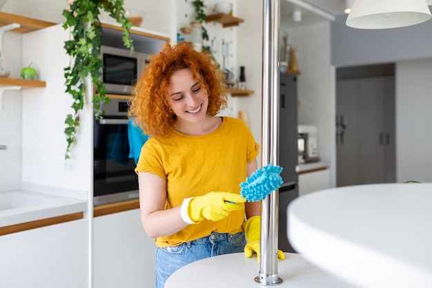 Portret van een mooie huisvrouw die stof schoonmaakt met beschermende gele handschoenen Vrouw gelukkig schoonmaakconcept