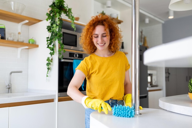 Portret van een mooie huisvrouw die stof schoonmaakt met beschermende gele handschoenen vrouw gelukkig schoonmaakconcept