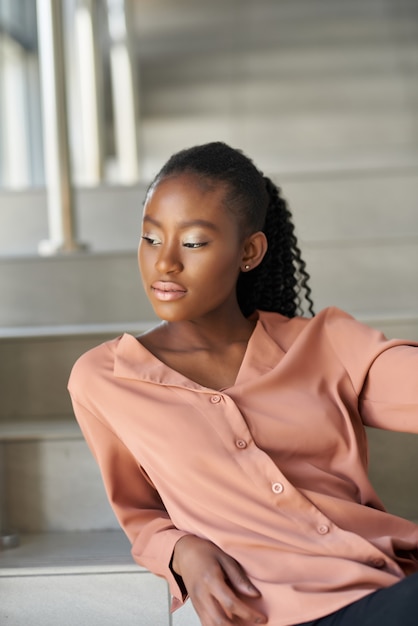 Portret van een mooie jonge Afro-Amerikaanse vrouw die tegen een trap in een gebouw staat