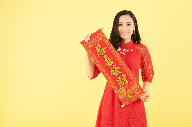 Portret van een mooie jonge Aziatische vrouw die coupletten vasthoudt met de beste wensen als decoratie voor de viering van het Chinese Nieuwjaar