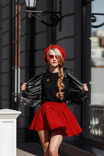 Portret van een mooie jonge blonde vrouw in een stijlvolle zwarte outfit die lacht