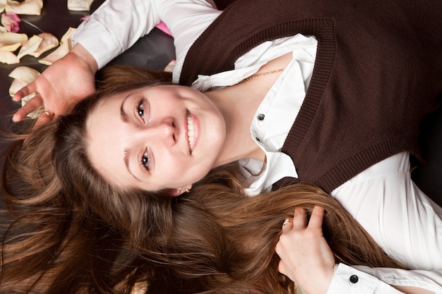 Portret van een mooie jonge brunette ligt met rozenblaadjes