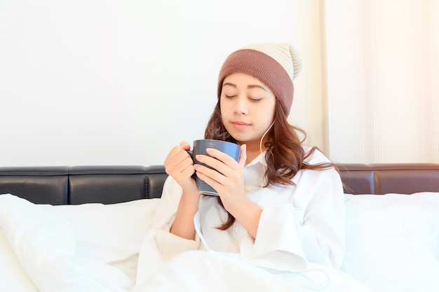 Portret van een mooie jonge dame die haar ochtendkoffie in haar slaapkamer drinkt