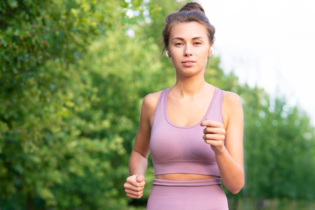 Portret van een mooie jonge peinzende vrouw die praat via een bluetooth-koptelefoon terwijl ze aan het sporten is...