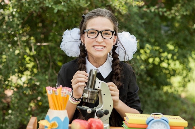 Portret van een mooie jonge schoolmeisjezitting bij een bureau