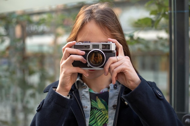 Portret van een mooie jonge toerist die foto's maakt met een vintage retro camera. street style. levensstijl