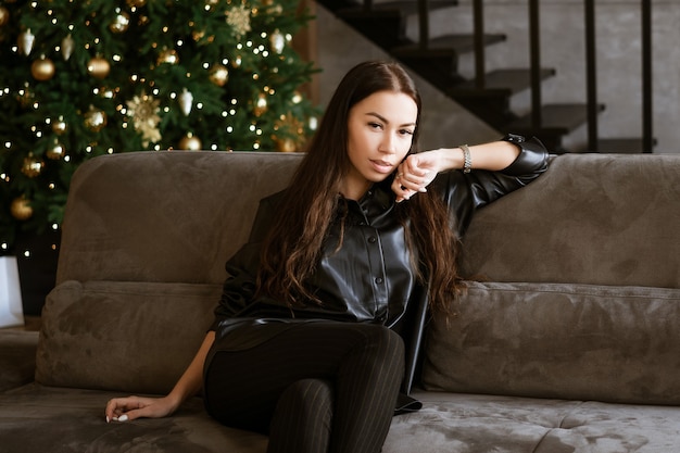 Portret van een mooie jonge volwassen brunette vrouw zittend op de bank in de woonkamer het meisje dat ik...