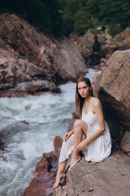 Portret van een mooie jonge vrouw die aan de rivier zit