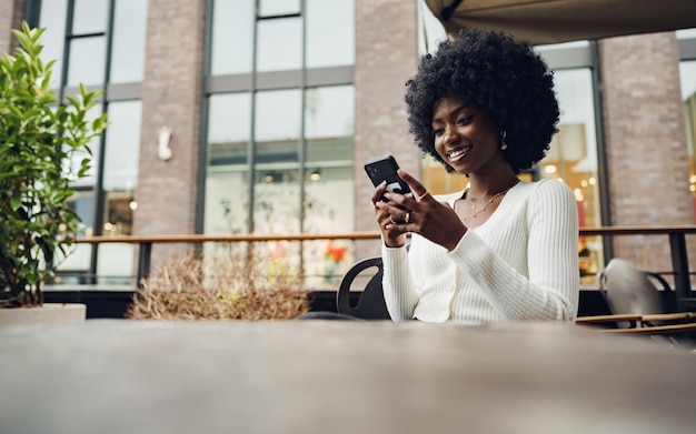 Portret van een mooie jonge vrouw die haar mobiel gebruikt in een café