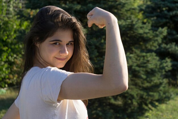 Foto portret van een mooie jonge vrouw die haar spieren buigt