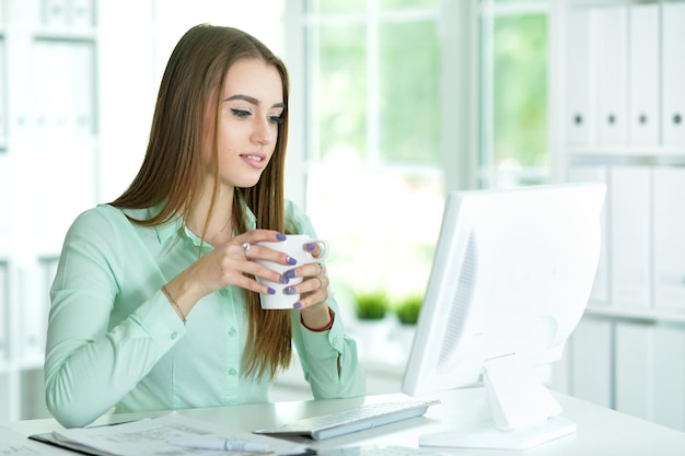 Portret van een mooie jonge vrouw die met de computer werkt