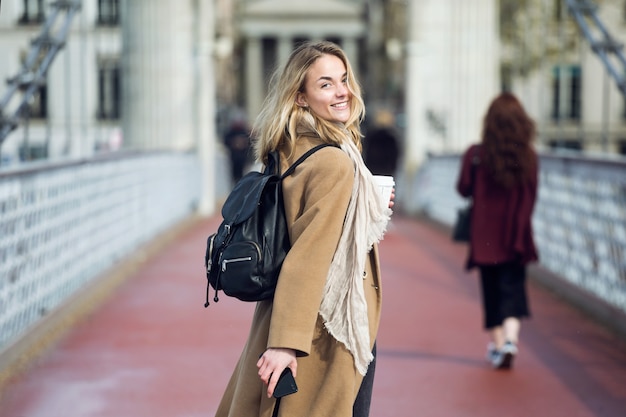 Portret van een mooie jonge vrouw die naar de camera kijkt terwijl ze op straat loopt.