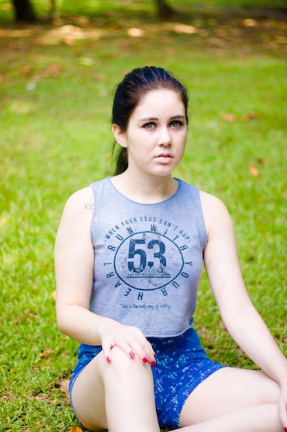 Foto portret van een mooie jonge vrouw die op een grasveld zit