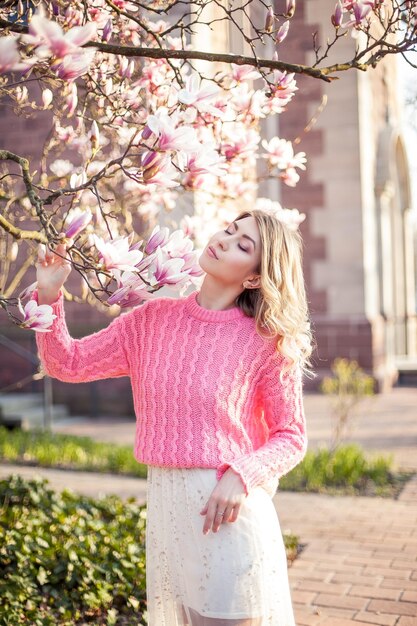 Portret van een mooie jonge vrouw in de buurt van een magnolia. Voorjaar.