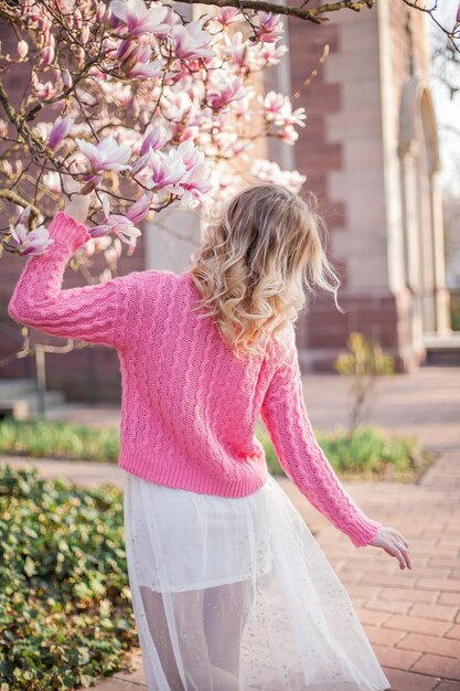 Portret van een mooie jonge vrouw in de buurt van een magnolia. Voorjaar.