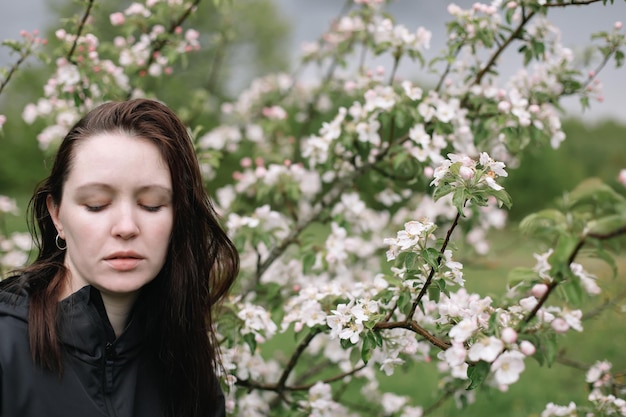 Portret van een mooie jonge vrouw in de lentetuin onder appelbloesem