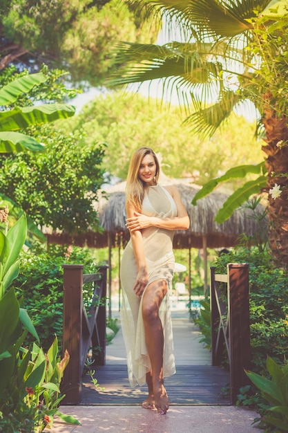 Portret van een mooie jonge vrouw in een lange jurk in een groene tropische tuin