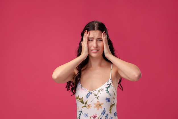 Portret van een mooie jonge vrouw in een lichte jurk die op een roze achtergrond staat in studiomensen sinds...