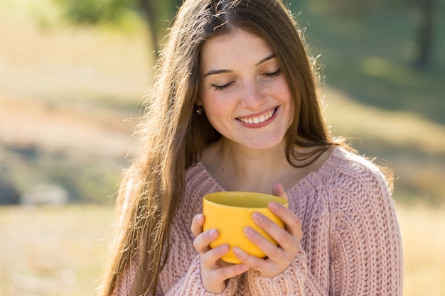 Portret van een mooie jonge vrouw in een stijlvolle gebreide trui die op het gouden herfstbos staat