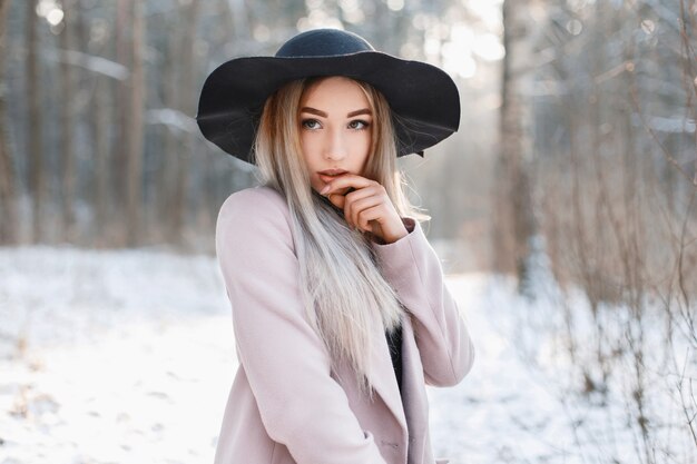 Portret van een mooie jonge vrouw in een zwarte hoed en een vintage jas in koele winterdag