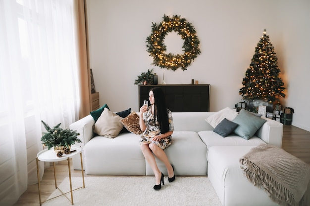 Portret van een mooie jonge vrouw in feestelijk kerst- en nieuwjaarsinterieur