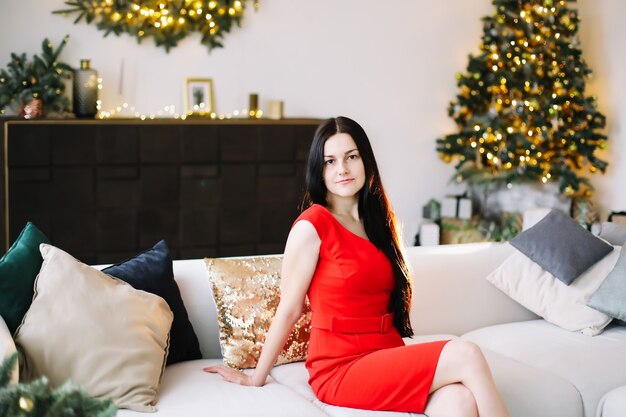 Portret van een mooie jonge vrouw in feestelijk kerst- en nieuwjaarsinterieur