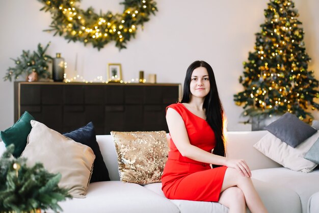 Portret van een mooie jonge vrouw in feestelijk kerst- en nieuwjaarsinterieur