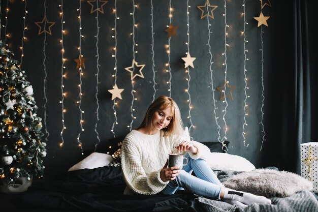 Portret van een mooie jonge vrouw in feestelijk kerst- en nieuwjaarsinterieur