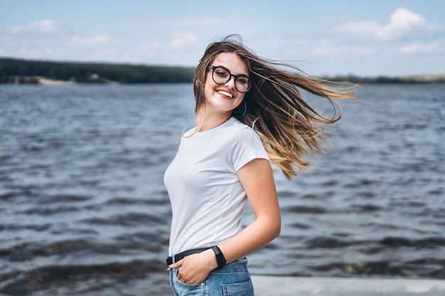 Portret van een mooie jonge vrouw in stijlvolle glazen, uitzicht op het meer