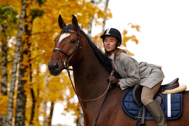 Portret van een mooie jonge vrouw met een bruine paardrijdende herfstdag