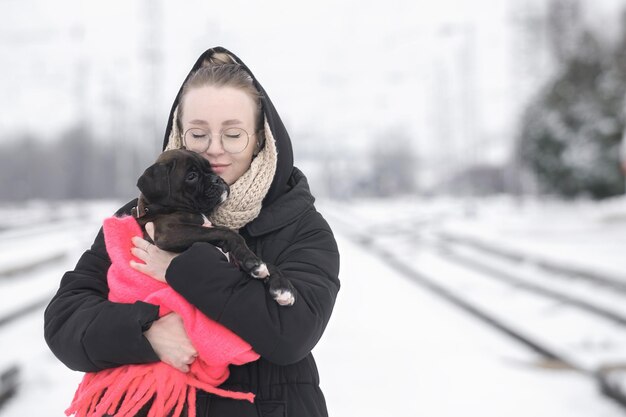 Portret van een mooie jonge vrouw met een Duitse bokserpuppy op een winterwandeling